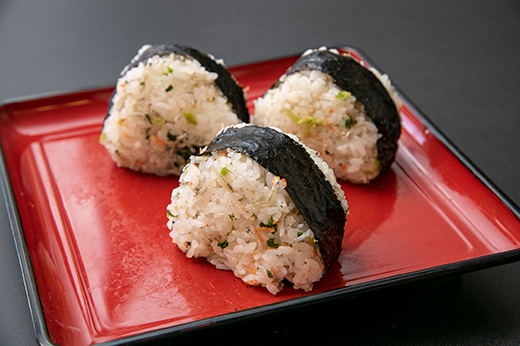 混ぜご飯のおにぎりが赤い盆に並ぶ